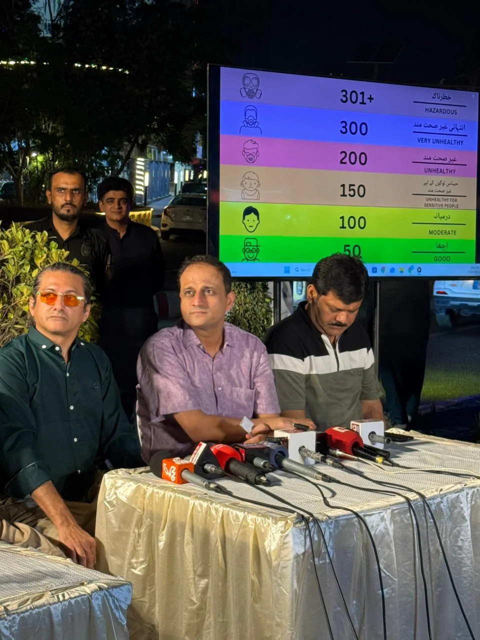 Air quality panelists speaking beside a public monitoring display in Karachi